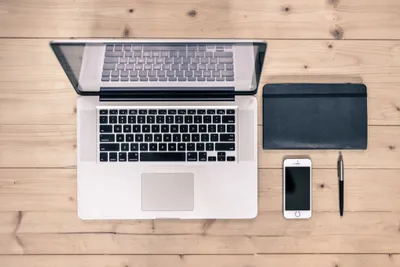 Workspace with laptop, smartphone, and notebook on a wooden desk