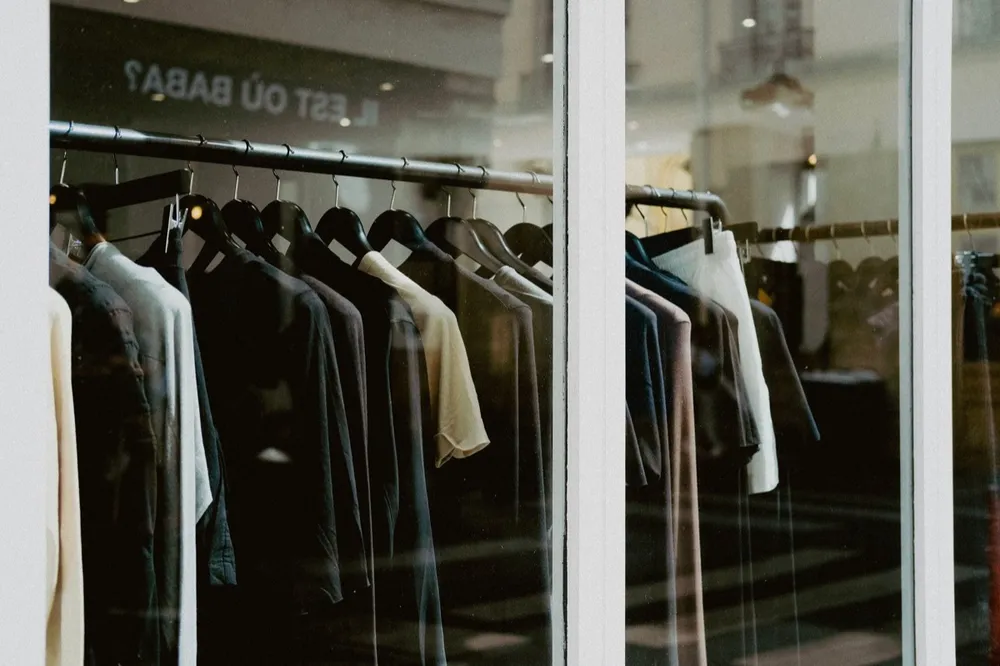 ملابس معلّقة على رفوف في واجهة متجر أزياء